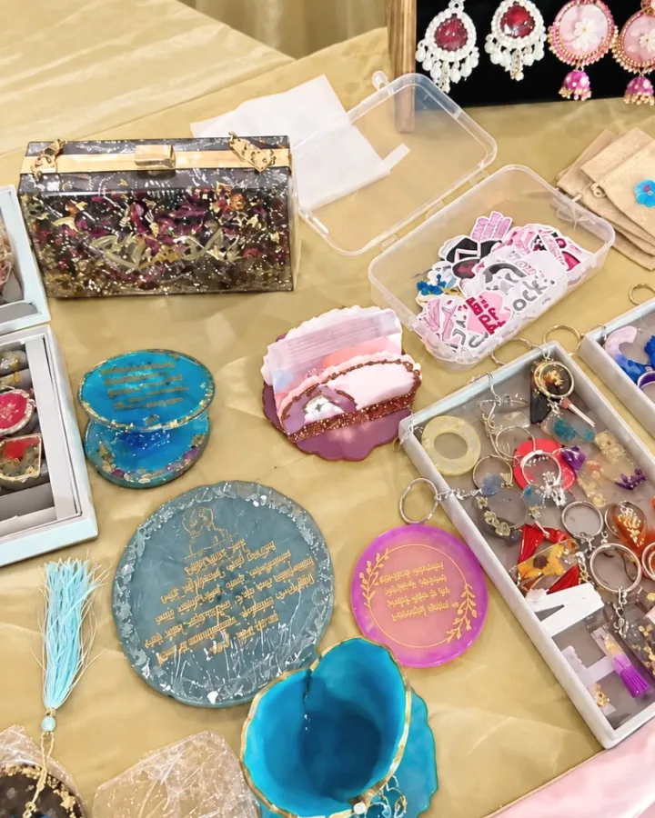 A Mystic Moldings exhibition table with a petal clutch, resin trays and coasters, keychains and a rack of pendants and earrings