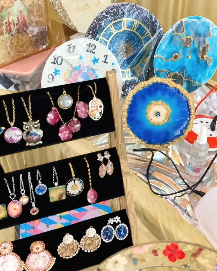Resin wall clocks, a photo frame and a rack of pendants and earrings at a Mystic Moldings exhibition stall