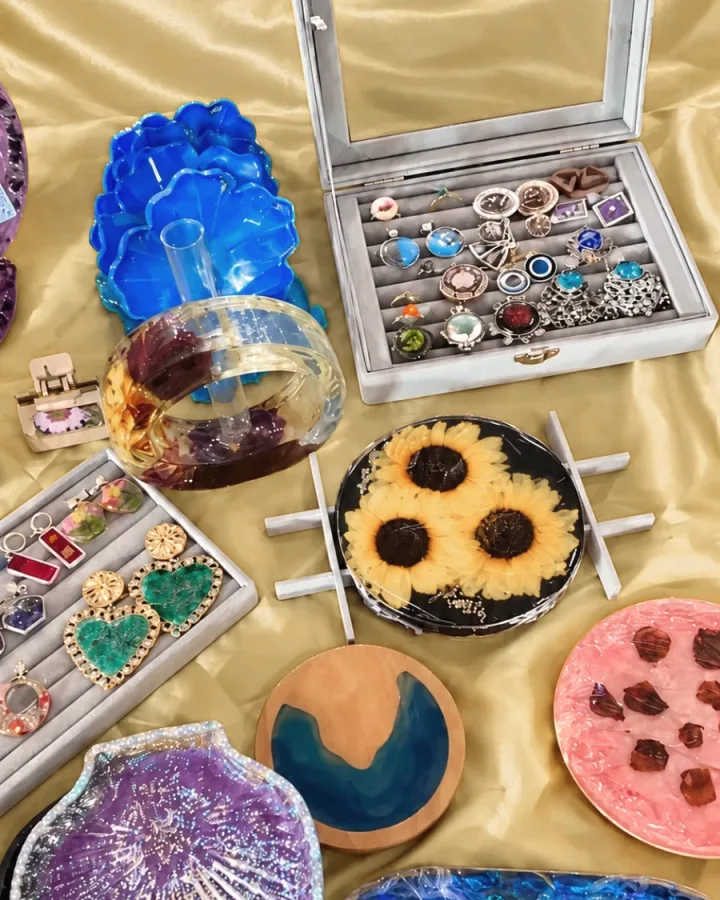 A box of resin rings, a sunflower tray, a flower bangle and resin trays laid out at an exhibition