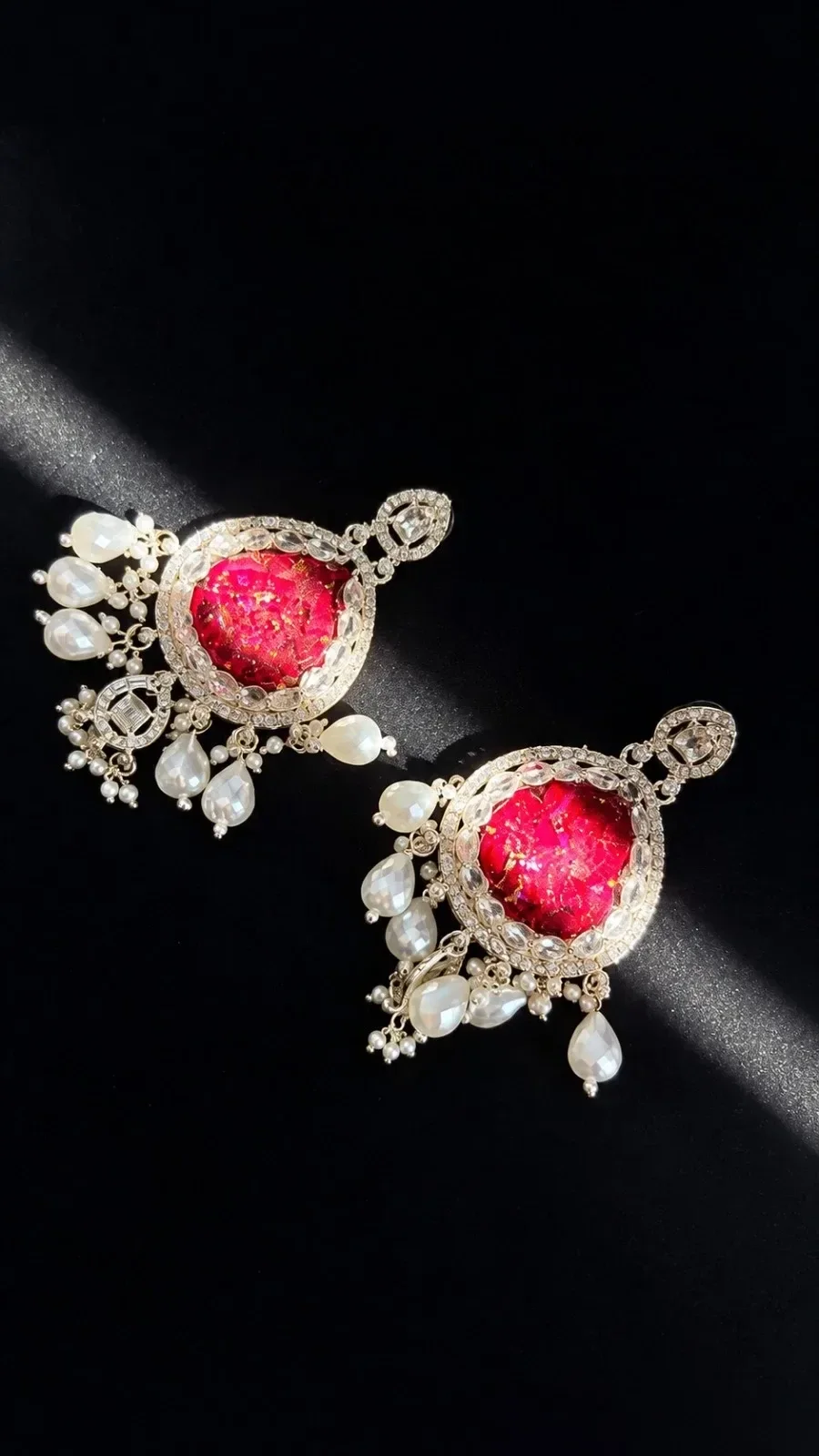 Chandbali earrings made with real red rose petals set in resin, framed in kundan crystals with pearl drops, in a beam of light